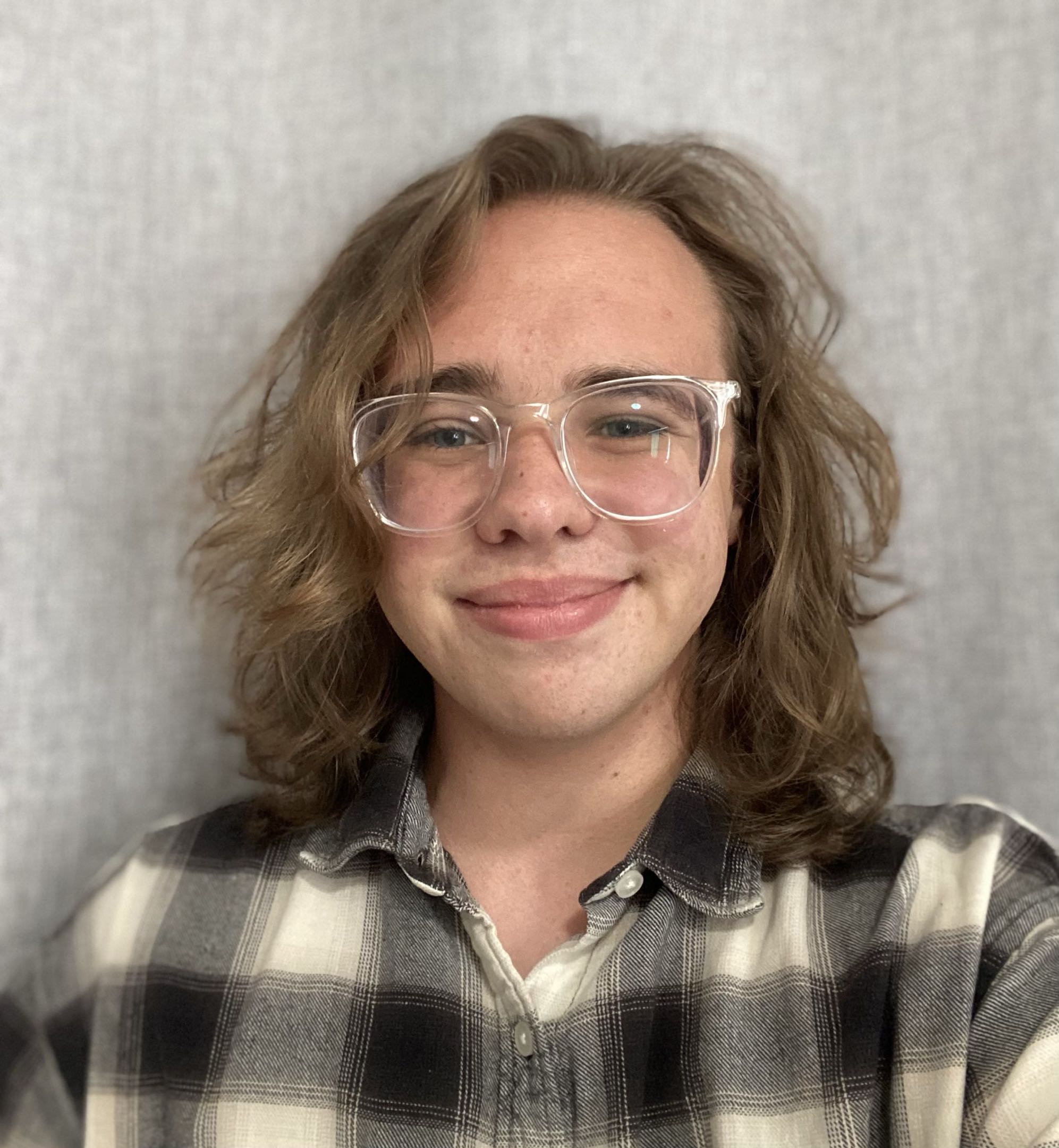 Photo of Alex Bregy, who is white with light brown shoulder length hair and glasses. 